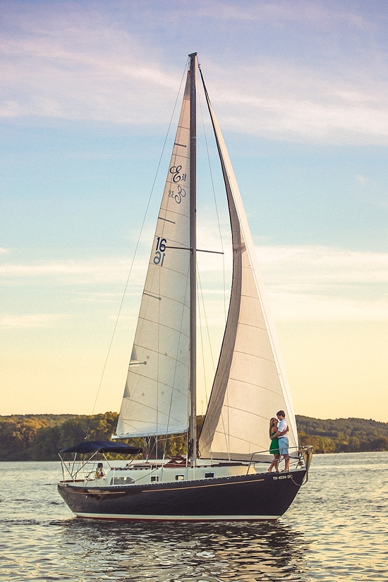 Couple embracing on a sailboat, sailing on calm water at sunset