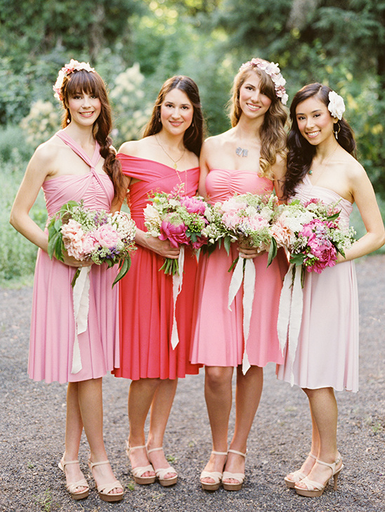 Bridesmaids in pink dresses holding flower bouquets and smiles