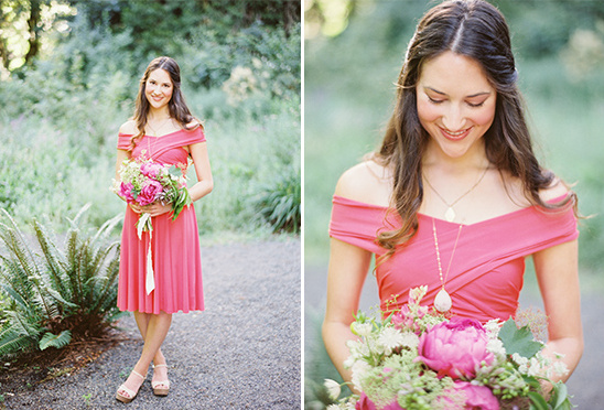 Woman in pink dress holding flowers smiles outside