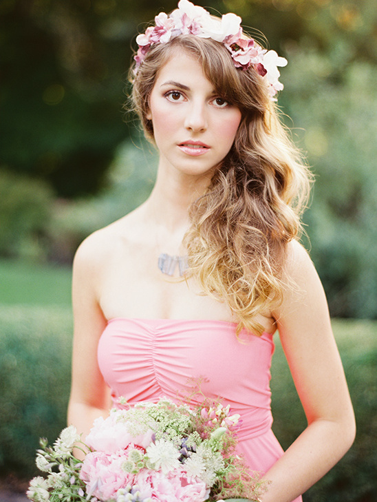 Beautiful woman in pink dress with flower crown holding flowers