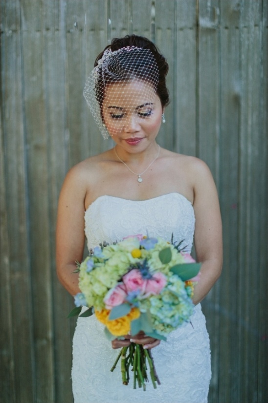 Bride holding colorful bouquet with delicate veil on her head