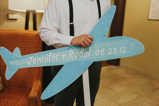 Man holding a blue airplane prop with names Jennifer and Rodel