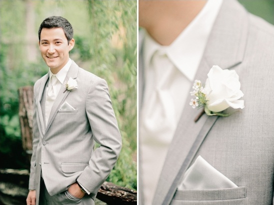 Groom in a light gray suit smiling, wearing a rose boutonniere