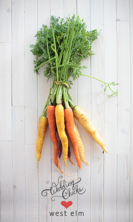 Bunch of colorful carrots with fresh greens on a wood background