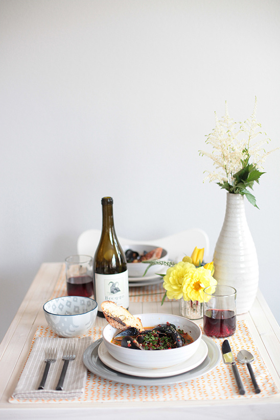 Cozy dinner table setting with mussels, wine, and flowers