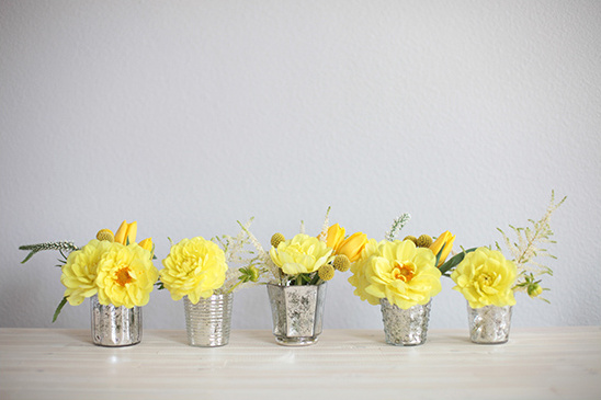 Arrangement of vibrant yellow flowers in silver vases