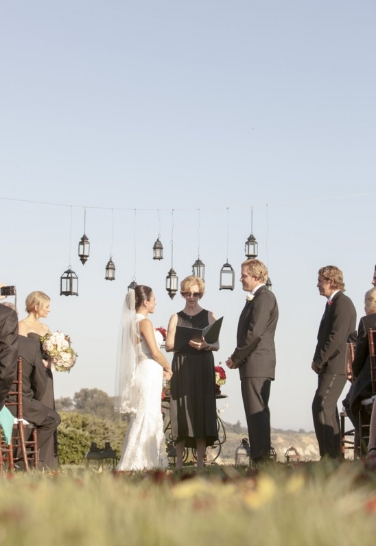 Outdoor wedding ceremony with bride, groom, officiant, and guests