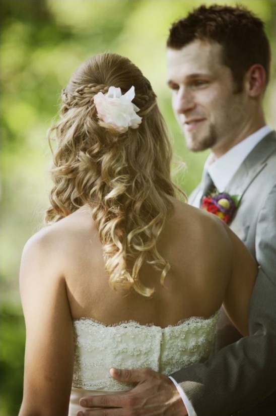 Bride with curly hair and flower, embraced by groom