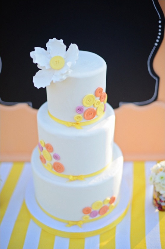 Three-tiered white wedding cake with colorful buttons