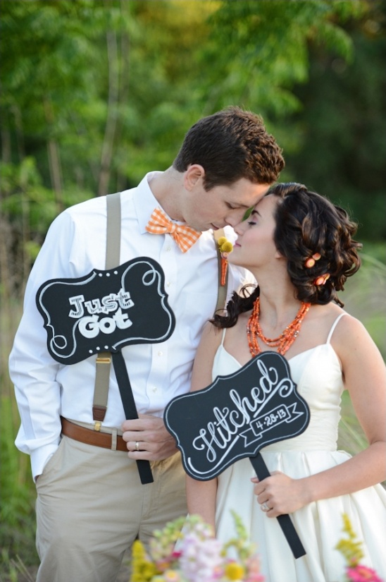 Newlywed couple holding Just Got Hitched signs