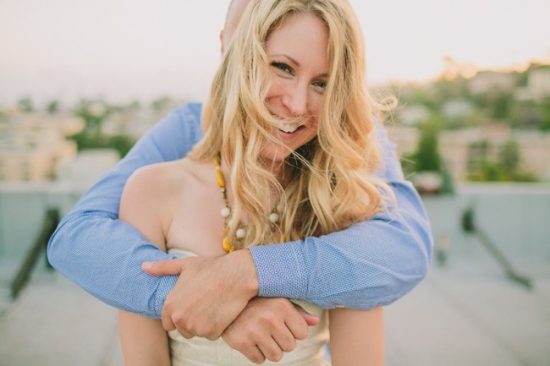 Couple hugging on rooftop smiling candidly