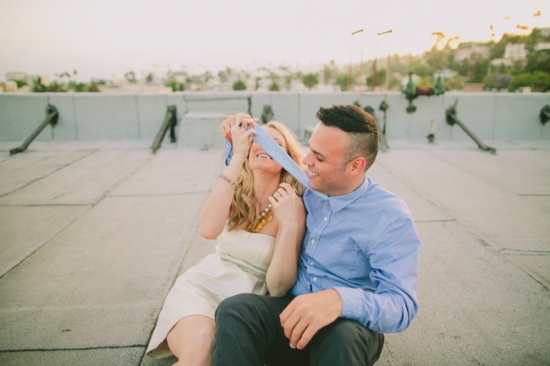 Playful couple on rooftop with tie over her face