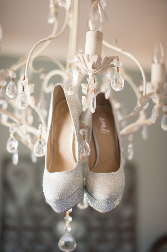 Sparkling wedding heels hanging from a chandelier