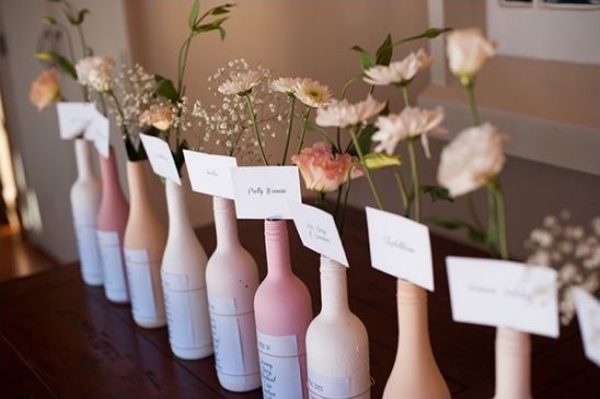 Pastel wine bottle centerpieces with floral arrangements and name cards