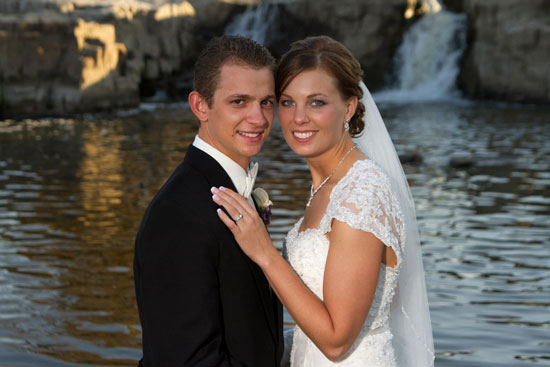 Happy newlywed couple posing by a waterfall