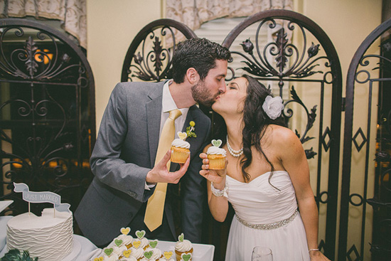 Newlyweds share a kiss with wedding cupcakes in hand