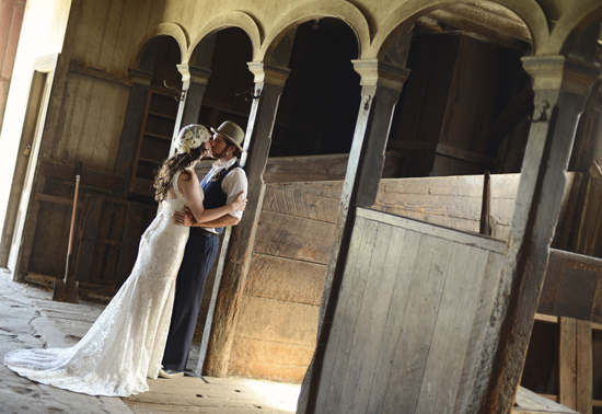 Rustic wedding couple kissing under arched entryway