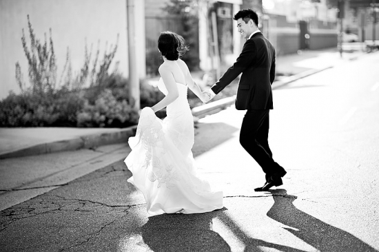 Black and white image of bride and groom running