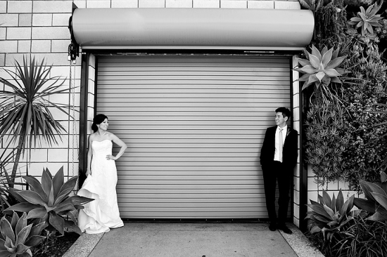 Black and white wedding photo by an industrial door