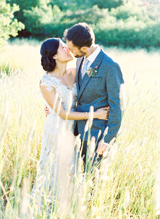 Bride and groom kissing in a sunlit meadow wedding