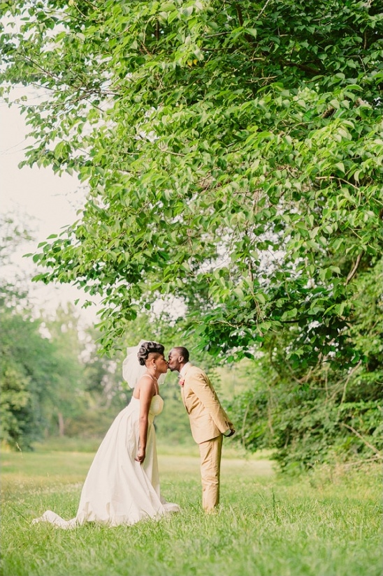 Bride and groom share a kiss under a tree