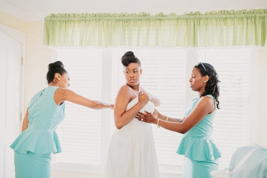 Bridesmaids help bride with wedding dress