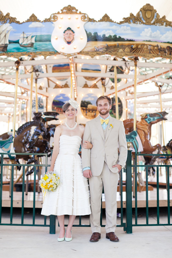 Bride and groom pose in front of carousel on wedding day