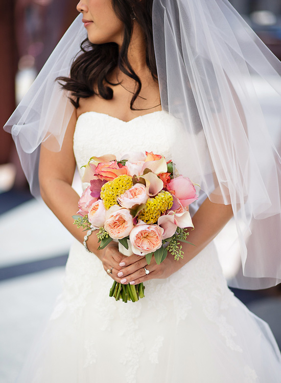 A wedding bouquet in peach, butter yellow, white, green, and dusty rose