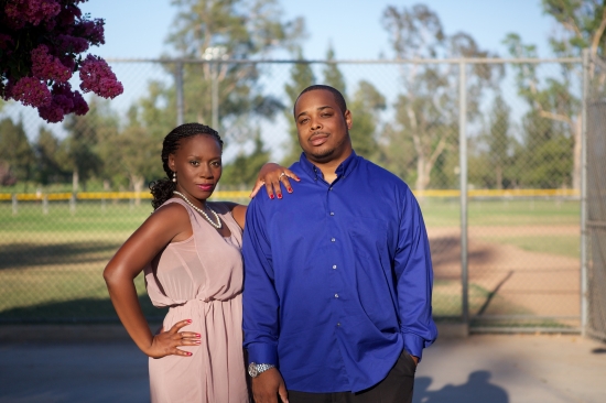 Happy couple posing outdoors near a baseball field