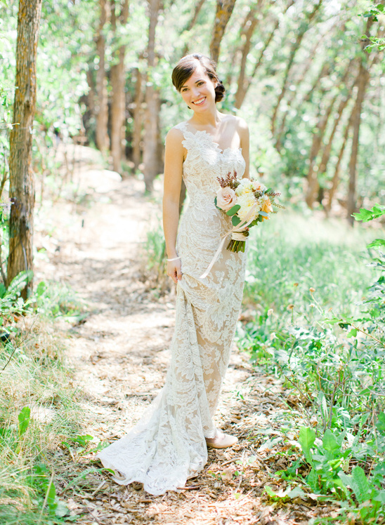 Bride in lace wedding dress smiles on path