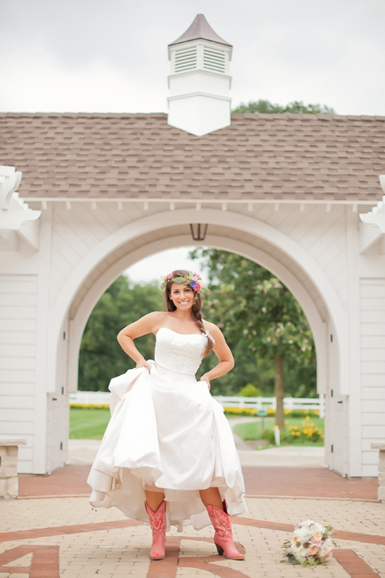 Bride in gown and pink boots stands at wedding venue