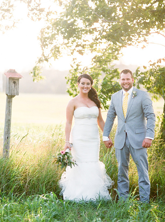 Happy bride and groom in field at sunset