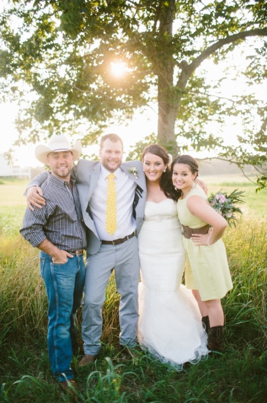 Happy wedding party poses outdoors under a tree