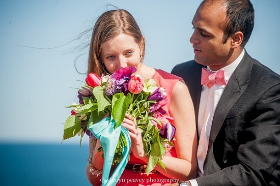 Bride smelling colorful wedding bouquet with groom