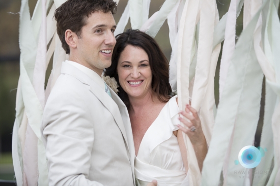 Happy wedding couple posing in front of ribbon decor
