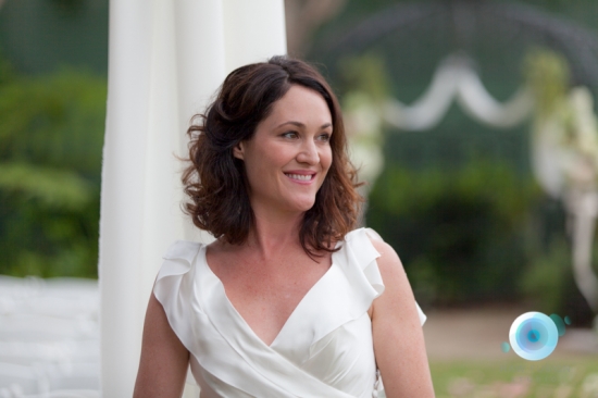 Woman in white dress smiles at an outdoor wedding