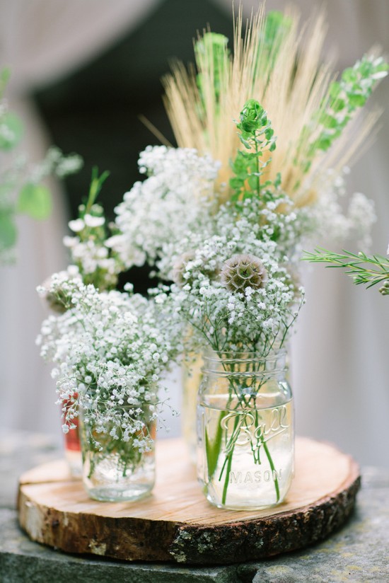 Mason jar vases with baby's breath on a wood slice