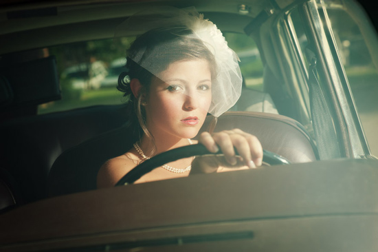 Bride in vintage car looking thoughtfully out the window