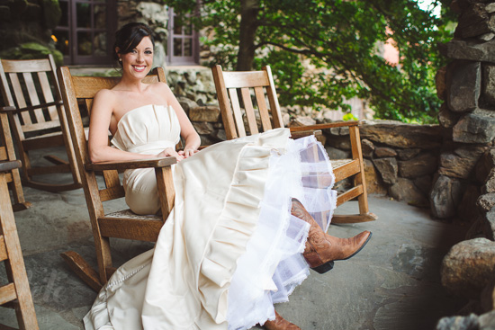 Bride in wedding dress and cowboy boots on porch swing