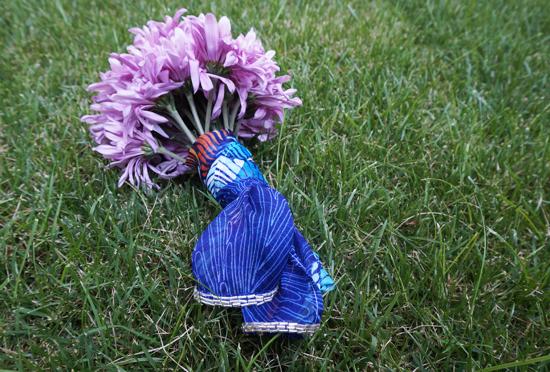 Purple chrysanthemum bouquet wrapped in blue fabric on grass