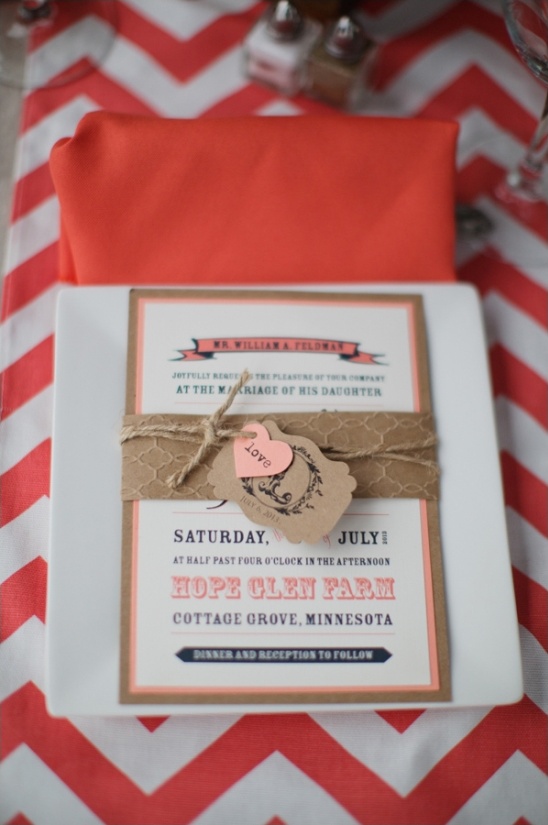 Wedding invitation card on plate with orange chevron tablecloth
