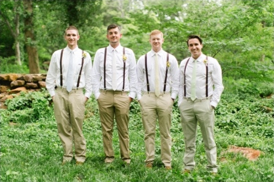 Groomsmen in khaki pants and suspenders pose outdoors