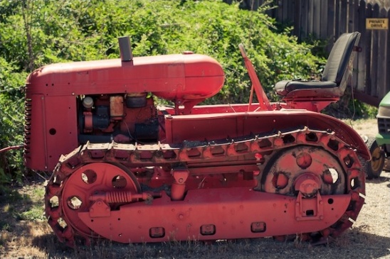 Vintage red crawler tractor with tracks in farmyard