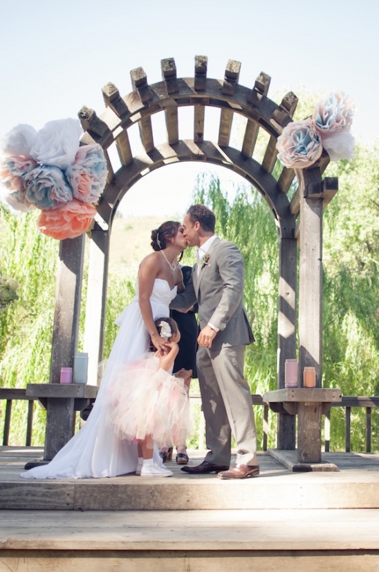 Bride and groom kissing under floral wedding arch