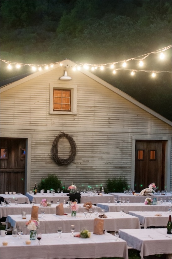 Outdoor wedding reception with string lights at dusk