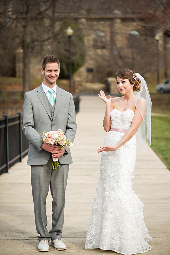 Bride gesturing questioningly to groom holding flowers