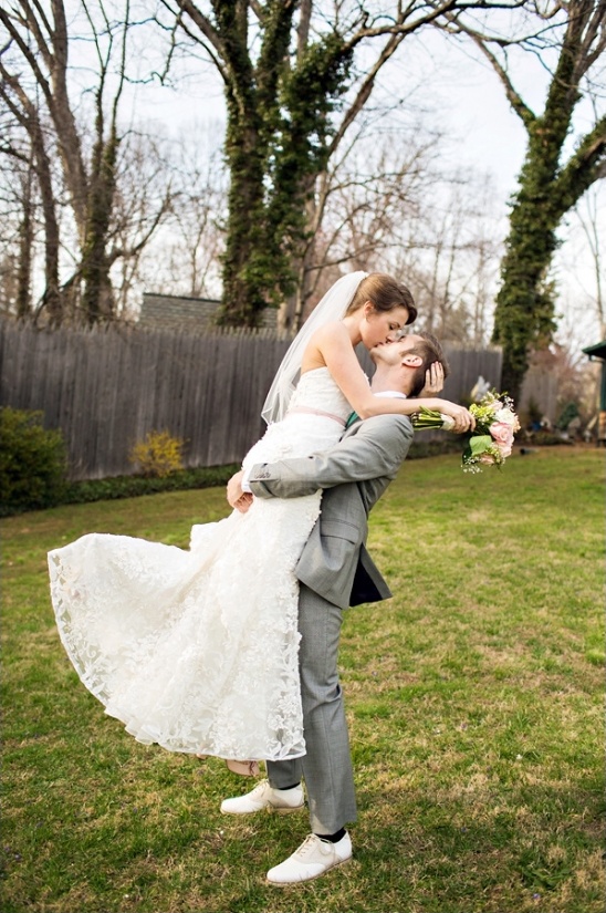 Groom lifts bride, sharing a loving kiss outdoors