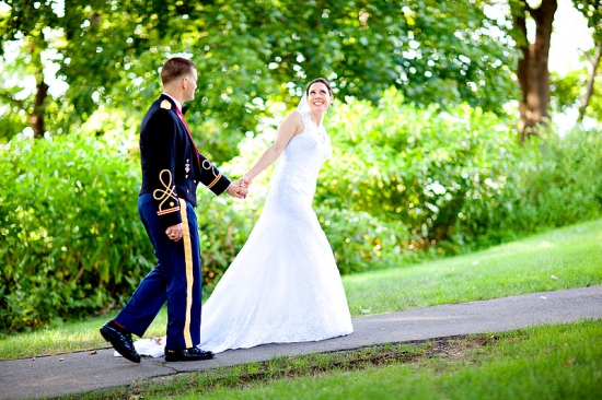 Couple in uniform and wedding dress walking hand in hand