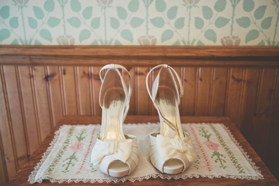 Elegant ivory wedding shoes with bows on a decorative table