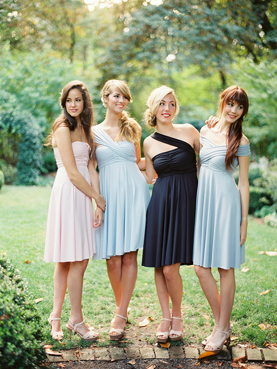 Four bridesmaids in pastel dresses pose outdoors
